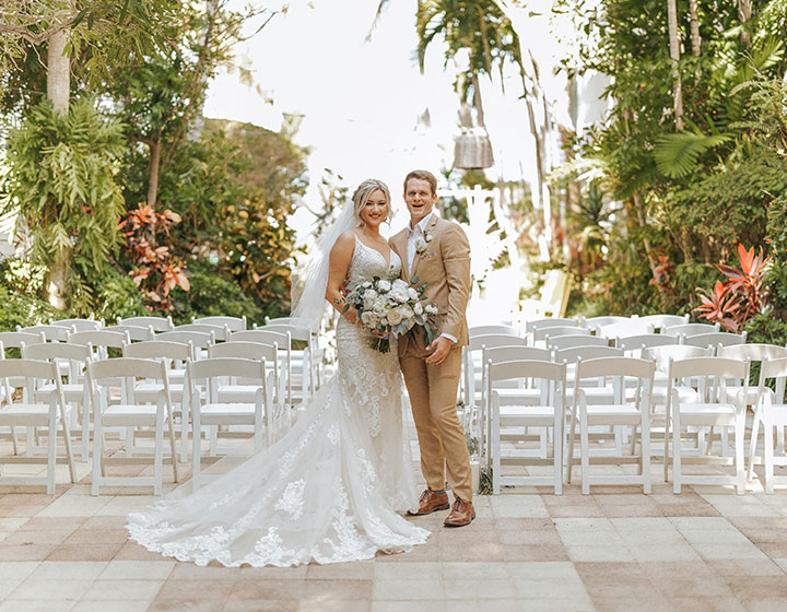 bride and groom in front of white chairs for ceremony at kimpton surfcomber hotel