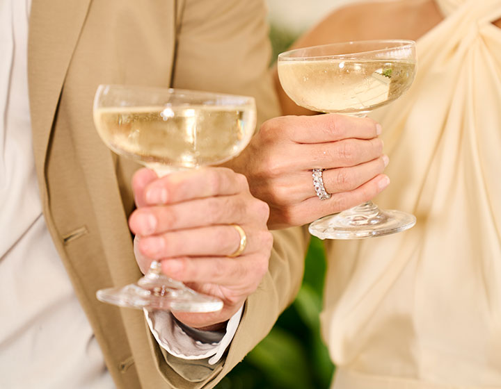 Bride and groom lounge on sofa with bouquet of flowers